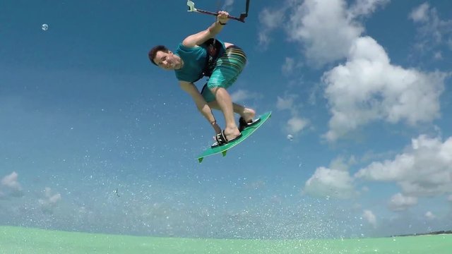 SLOW MOTION: Happy smiling kiter kiteboard jumping in tropical island lagoon