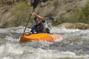 Young Caucasian man kayaking on mountain river