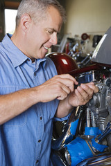 Happy male mechanic repairing motorcycle engine