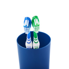 Pair of toothbrushes in blue plastic cup isolated over white background