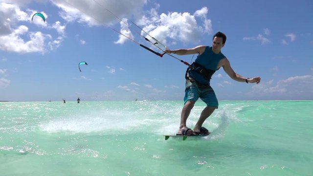 SLOW MOTION: Extreme kite surfer kiting and jumping, splashing water into camera