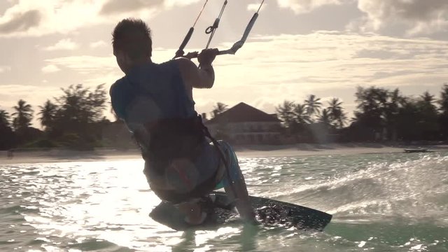 SLOW MOTION: Extreme surfer man kiteboarding and jumping high at sunset