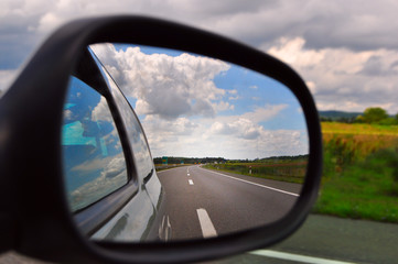 Fototapeta na wymiar Traveling, rear view mirror road view and clouds