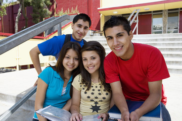 Portrait of happy high school students studying together on school steps