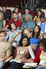 Portrait of a young female student raising hand to answer a question in the classroom