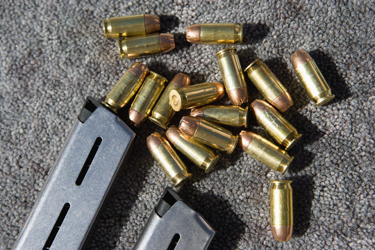 Closeup of gun magazines and bullets on grey carpet