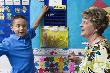 Teacher teaching elementary student to count money in math class