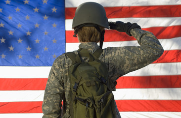 Rear view of a female soldier saluting in front of American flag