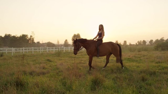 SLOW MOTION: Pretty young blonde girl bareback riding on misty summer morning