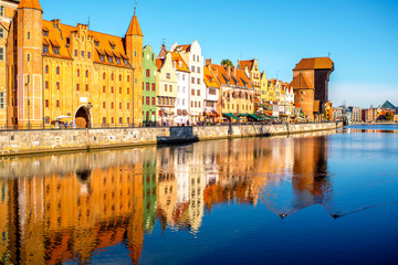 Naklejka na ściany i meble Morning view on the riverside of Motlawa river with beautiful buildings and famous historic gate of the old town in Gdansk, Poland