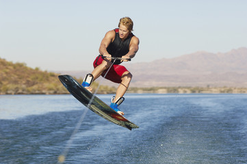 Young man wakeboarding on lake - obrazy, fototapety, plakaty