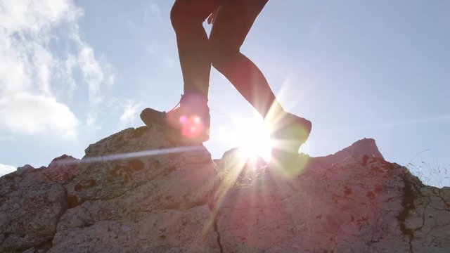 LOW ANGLE: Unrecognizable female hiker in leather boots climbing mountaintop