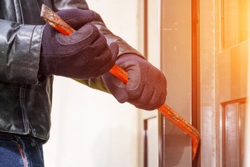 Burglar wearing leather coat breaking in a house