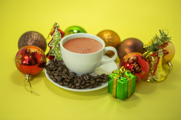 Cup of coffee and christmas toys on yellow background.