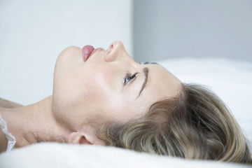 Closeup of thoughtful young woman lying in bed