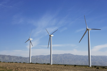 Fototapeta premium Three wind turbines in desert against blue sky