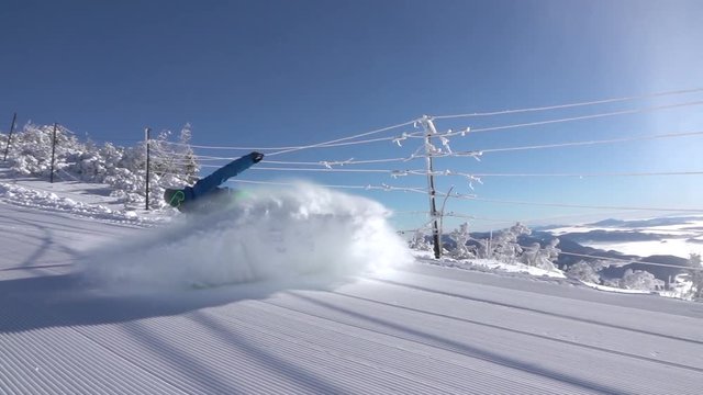 SLOW MOTION: Snowboarder splashing freshly groomed snow on mountain ski slope