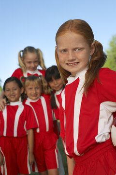 Portrait of girl soccer player with teammates in the background