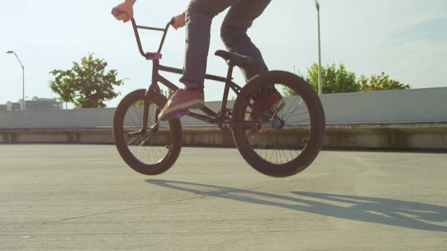 SLOW MOTION CLOSEUP: Bmx biker jumping 360 rotation bunny hop trick in skatepark