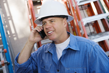 Male industrial worker using cell phone at workplace