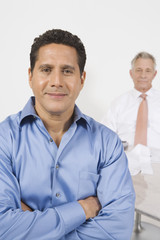 Portrait of a confident businessman with male colleague in background