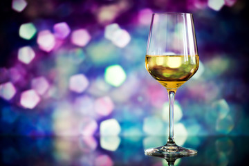 glass of white wine against a glowing bokeh - copy space, select