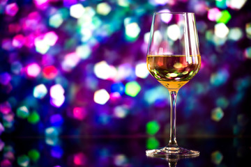glass of white wine against a glowing bokeh - copy space, select