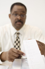An African American accountant with expense receipt at office