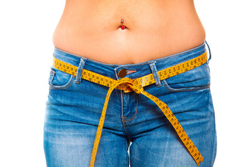 a slender young woman in jeans with a tape measure after a diet