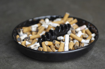 Closeup of ashtray full of cigarette butts on colored background