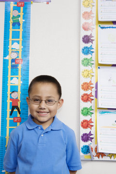 Portrait of a cute little boy measuring height in classroom