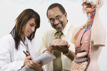 Professor assisting female high school student in science lab