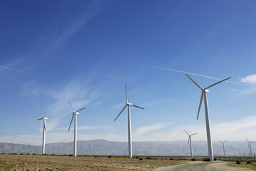 Wind turbines generating electricity in desert against blue sky