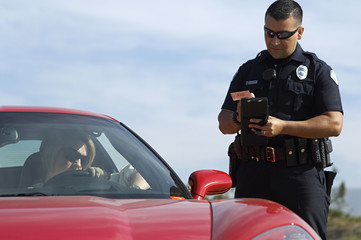 Traffic cop writing a ticket for woman sitting in sports car