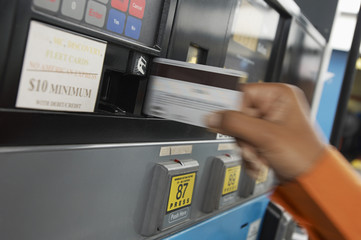 Blurred motion of a person paying with credit card at gas pump