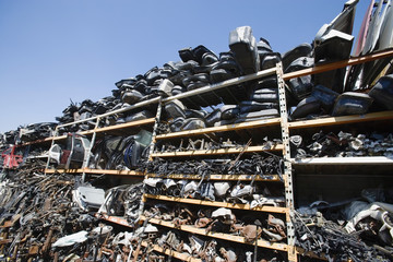 Broken and wrecked vehicle parts in rack at junkyard