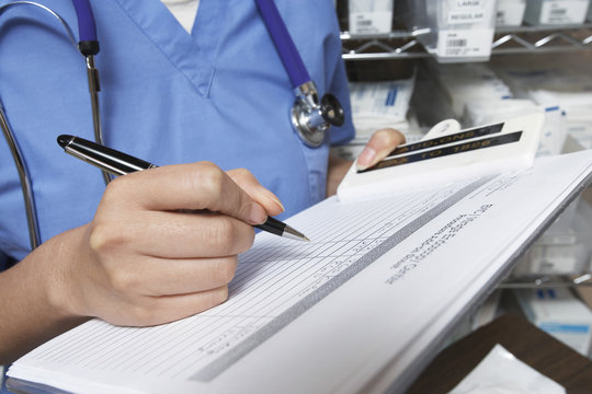 Midsection of female doctor writing in patient's medical chart