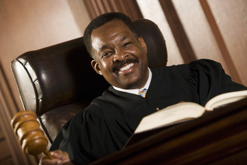 Portrait of a happy judge with gavel and book in the courtroom