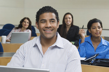 Happy businessman in presentation with female business colleagues sitting in the background © MDBPIXS