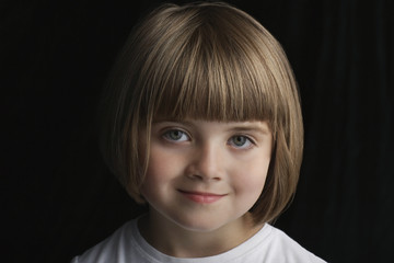 Closeup portrait of happy cute little girl with short hair isolated on black background