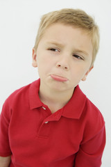 An upset little boy in a casual red t-shirt isolated over white background