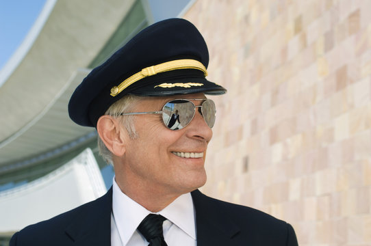 Closeup of a happy senior airline pilot outside building
