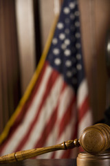 Closeup of a wooden gavel lying in courtroom with American flag in the background