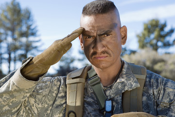 Portrait of a male soldier in camouflage uniform saluting