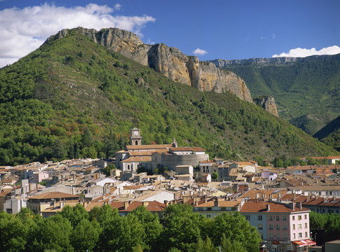 Houses and church with bell tower below a rocky hill at Digne les Bains, Alpes de Haute Provence, Provence, France