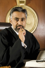 Portrait of an Asian judge sitting with law book in courtroom