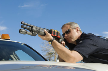 Caucasian male police officer aiming shotgun