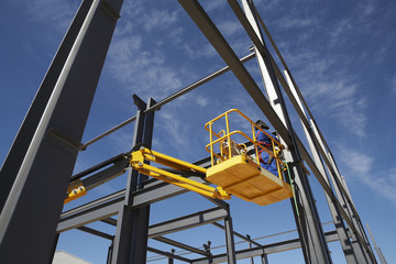 Welder working from cherry picker on steel framing structure