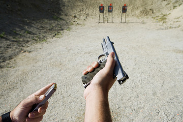 Closeup of man's hand loading hand gun at firing range