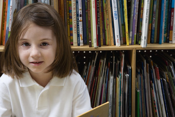 Portrait of a preadolescent girl in library against books arranged in shelves